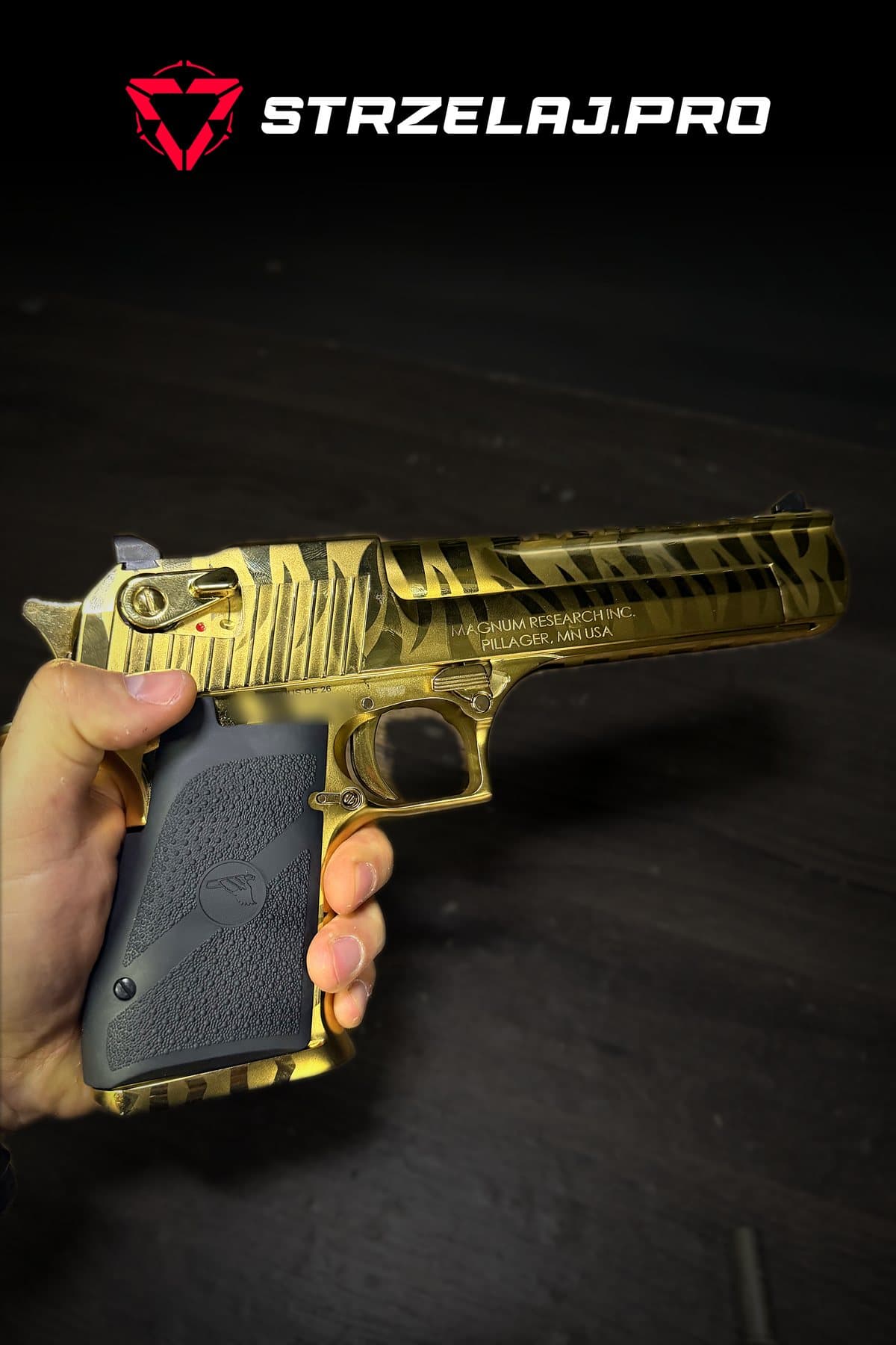Desert Eagle Mark XIX .44 Magnum Titanium Gold Tiger Stripes trzymany w dłoni, lewa strona, logo STRZELAJ.PRO