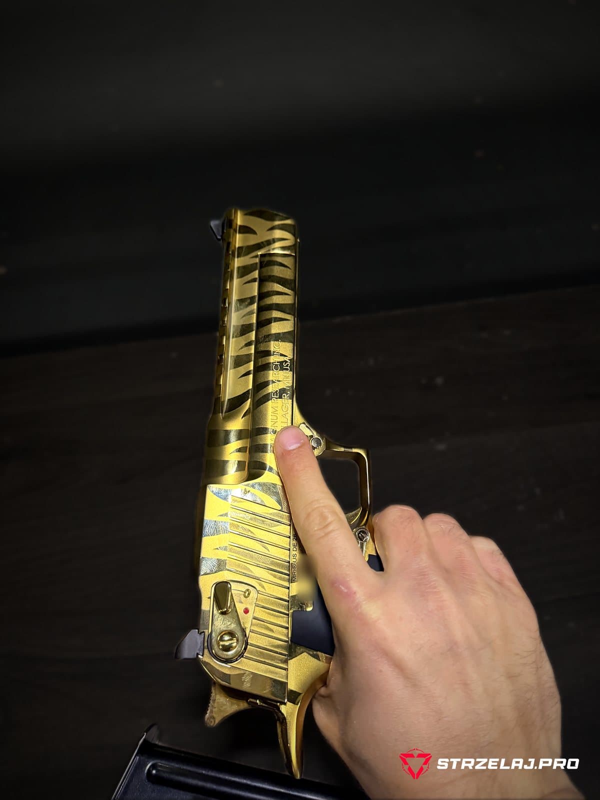 Desert Eagle .44 Magnum widziany z góry na stole strzeleckim, obok magazynek